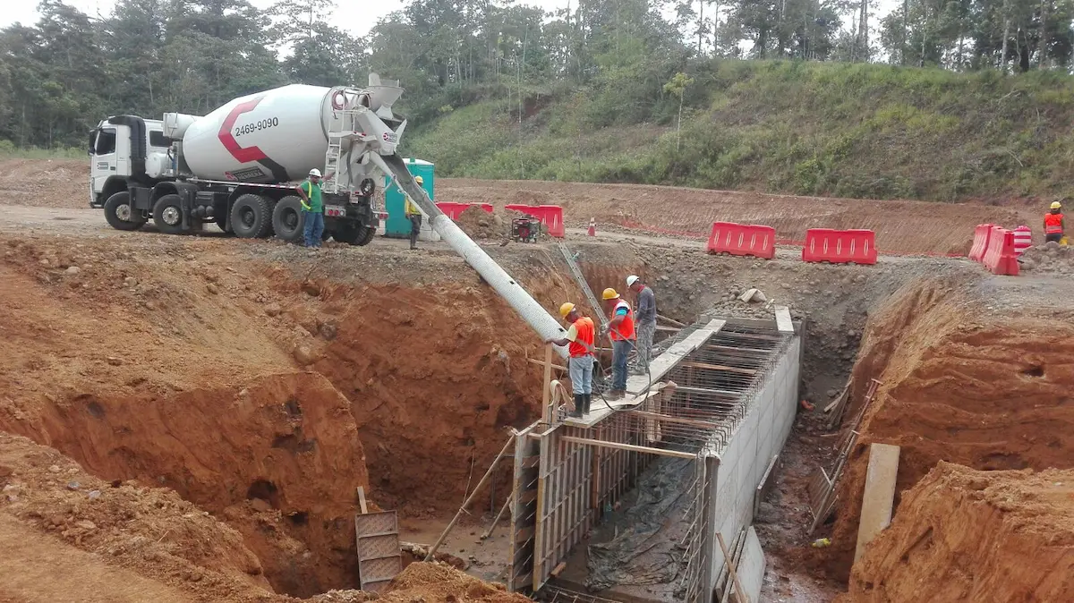 Trabajadores y camión mezclador de concreto durante estabilización de talud en Balsa Inferior – Constructora Herrera